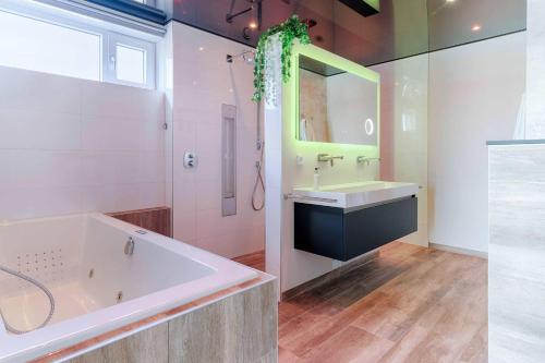 a bathroom with a tub and a sink and a mirror at Wellness aan de Vecht - Begane grond by Droomvilla in Dalfsen