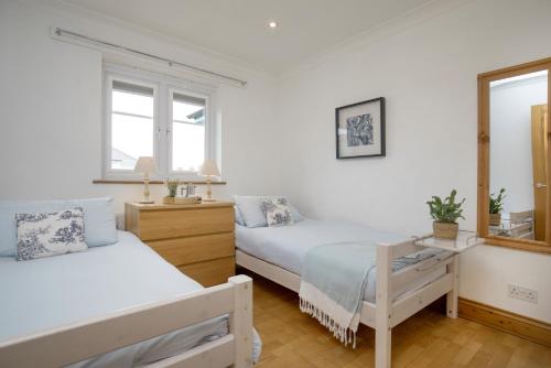 een witte slaapkamer met 2 bedden en een spiegel bij Balamory in Exmouth