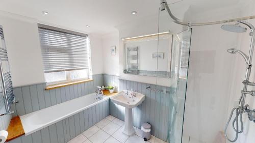 Un baño con lavabo, bañera y ducha. en Sea Mist, en Sidmouth
