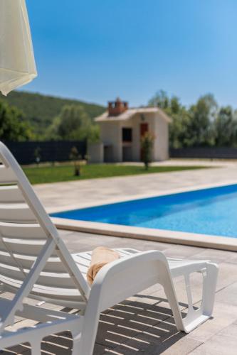 a white lawn chair sitting next to a swimming pool at Kuća Grab in Grab