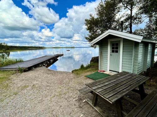 a small house with a bench next to a lake at Vista Vibes Glamping -Chillbillystuga in Grillby