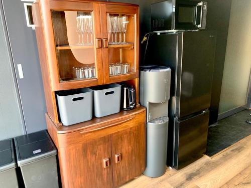 a kitchen with a wooden cabinet with a refrigerator at Black Penthouse Naha 最大12名宿泊可 118平米 国際通り沿い 牧志駅 徒歩5分 in Naha