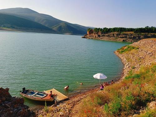 a boat in a lake with people in the water at SuperPanorama GuestHouse in Kukës