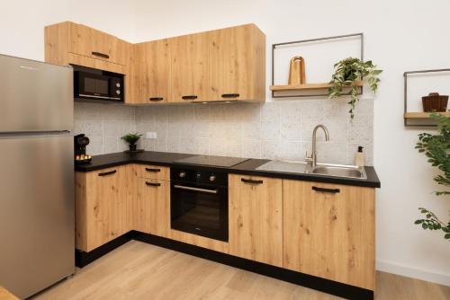 une cuisine avec des armoires en bois et un réfrigérateur en acier inoxydable dans l'établissement Balda'Quand Médiéval, à Carcassonne