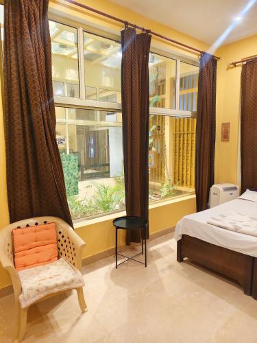 a bedroom with a bed and a chair and a window at Devi music ashram in Rishīkesh