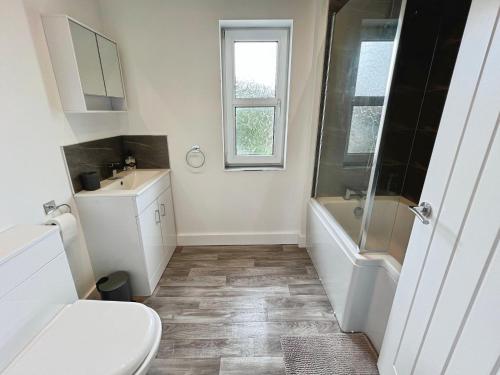 a white bathroom with a toilet and a sink at Cleethorpes Modern Home in Old Clee