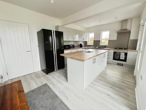 a kitchen with white cabinets and a black refrigerator at Cleethorpes Modern Home in Old Clee