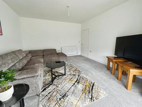 a living room with a couch and a flat screen tv at Cleethorpes Modern Home in Old Clee