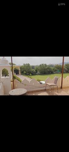 a patio with a chair and a table and a golf course at Yogi resort and restaurant in Ajmer