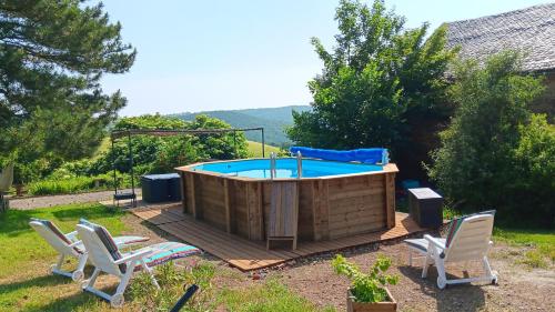 un jacuzzi dans une cour arrière avec des chaises autour dans l'établissement Le grand gîte, à Saint-Beauzély