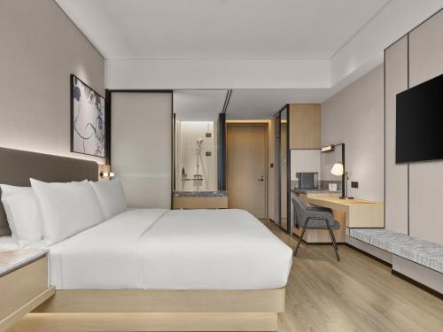 a bedroom with a large white bed and a desk at AC Hotel Suzhou Industrial Park in Suzhou