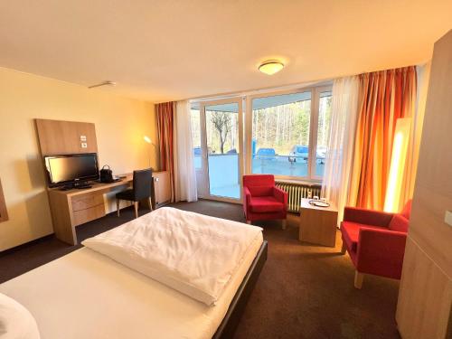 a hotel room with a bed and a desk and chairs at Schwarzwaldapartment Nr 23 30qm Doppelbett Modern in Altensteig