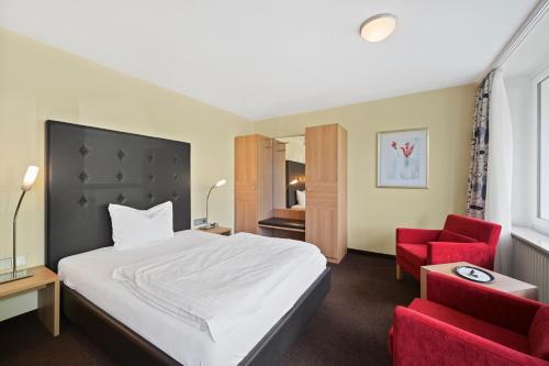 a hotel room with a bed and a red chair at Schwarzwaldapartment Nr 23 30qm Doppelbett Modern in Altensteig