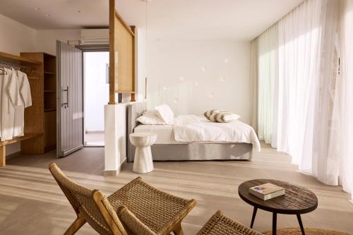 a bedroom with a bed and a table and chairs at Orias Luxury Suites Kythnos in Kithnos