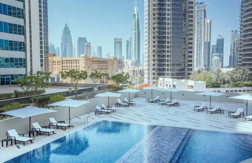 ドバイにあるLuxury Studios with Burj Khalifa View - Marquise Square Towerの建物の上に椅子とパラソルが置かれたプール