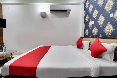 a bedroom with a large bed with red pillows at Super Hotel O Legacy Raebareli in Rāe Bareli