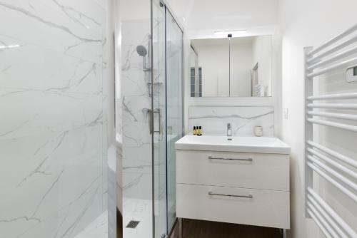 une salle de bain blanche avec un lavabo et une douche dans l'établissement Lueur des Années Dorées, à Carcassonne