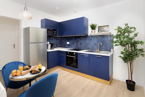 une cuisine avec des placards bleus et une table avec des fruits. dans l'établissement Lueur des Années Dorées, à Carcassonne