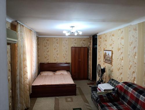 a bedroom with a bed and a couch at Квартира-аппартамент, 2 этаж in Chilanzar