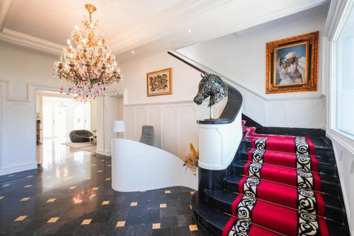 a room with a staircase with a red carpet and a chandelier at La Résidence in Rabat