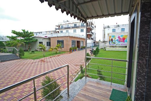 a balcony with a view of a park and buildings at Holiday Beach Resort !! Beach Distance 50 Mts !! in Mandarmoni