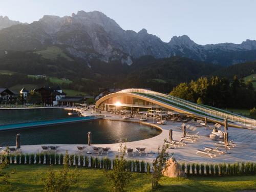 a bridge over a lake with mountains in the background at Hotel Krallerhof in Leogang