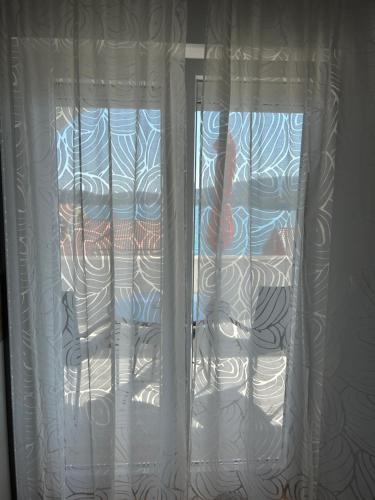 a window with white curtains in a room at Rooms Perina Tisno in Tisno