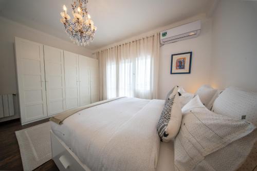 a bedroom with a white bed and a chandelier at Elegance in Télemly, View of Algiers Bay in LʼAgha