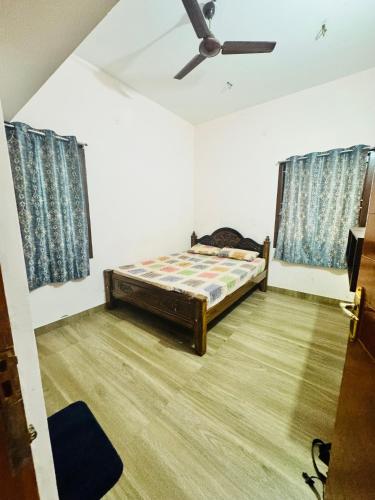 a bedroom with a bed and a ceiling fan at vilpati house in Kodaikānāl