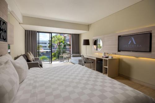 a hotel room with a large bed and a desk at Anathera Resort Kuta in Kuta