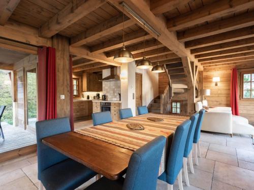 une salle à manger avec une table en bois et des chaises bleues dans l'établissement Chalet pour 8 avec cheminée, proche des pistes, WiFi, garage, non fumeur - FR-1-304-110, à La Clusaz