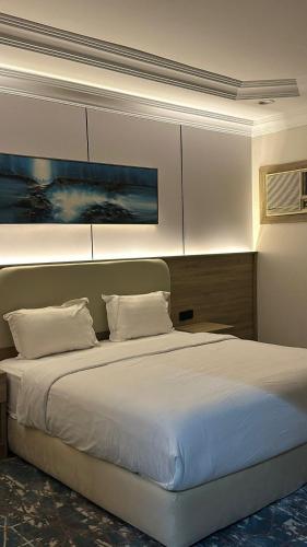 a bedroom with a large bed with white sheets at راحتي للشقق المخدومة in Taif