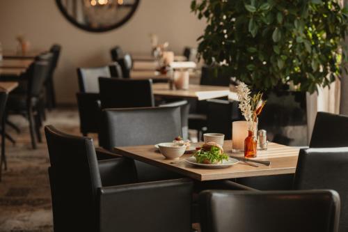 a table and chairs in a restaurant with a plate of food at Home Hotel Etage in Västerås
