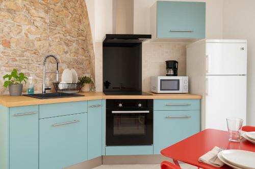 La cuisine est équipée de placards bleus et d'un réfrigérateur blanc. dans l'établissement Cannes Casa Pierra Apartment, à Cannes