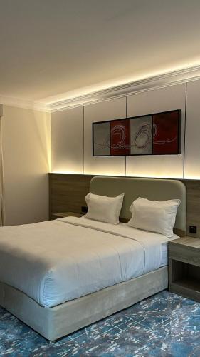 a bedroom with a large bed with white sheets at راحتي للشقق المخدومة in Taif