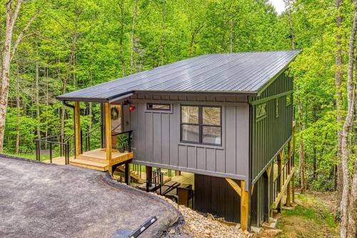 a green and gray tiny house in the woods at Peaceful Smoky Treehouse| Hot Tub • Hammock • Deck in Line Spring