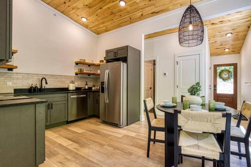 a kitchen with a table and a stainless steel refrigerator at Peaceful Smoky Treehouse| Hot Tub • Hammock • Deck in Line Spring