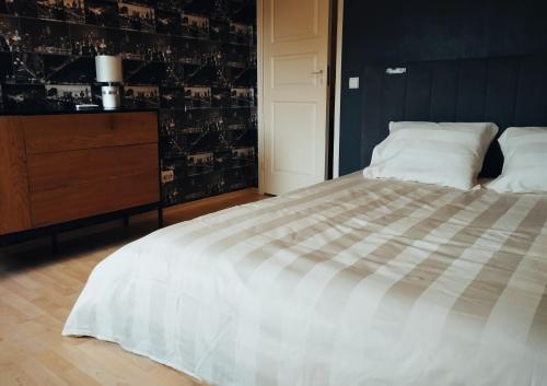 a bedroom with a large white bed and a dresser at Loo puhkemaja Saaremaal in Kudjape