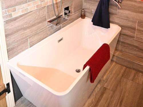 eine weiße Badewanne mit einem roten Handtuch darauf in der Unterkunft Petty Knowes Cottage in Newcastle upon Tyne