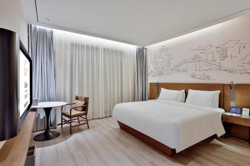 a bedroom with a bed and a desk and a tv at UrCove by Hyatt Jiashan Centre in Jiashan