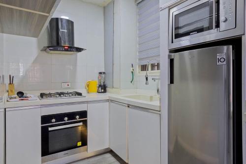 a kitchen with white cabinets and a stainless steel refrigerator at Stay Well Homes Comfortinn in Eregun