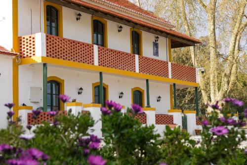 a yellow and white house with flowers in the foreground at Quinta da Varzea in Raposa