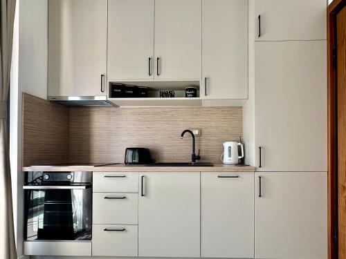 a kitchen with white cabinets and a sink at Isidora Seafront Apartments in Igalo
