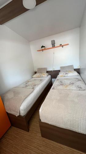 a room with two beds and a shelf on the wall at Zelena Laguna Mobile Homes in Poreč