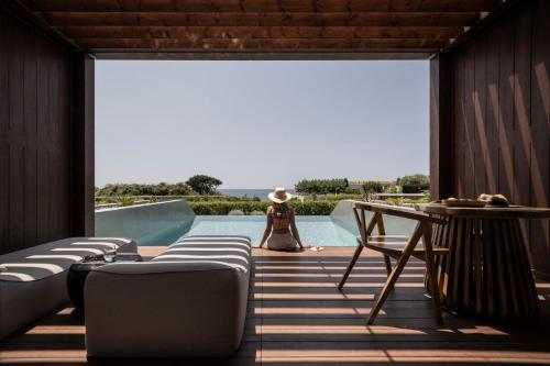 a woman is sitting on the deck of a house at Meraviglia Slow Living in Preveza