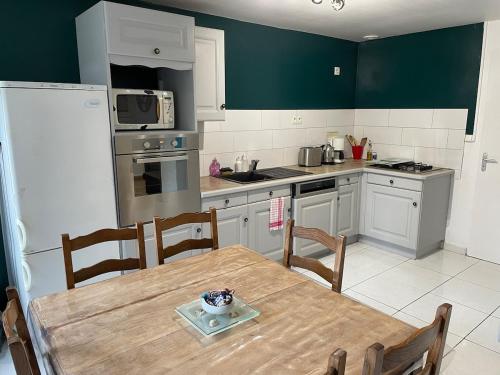 a kitchen with a wooden table and a refrigerator at Maison dans plus beau village de France in Sainte-Suzanne