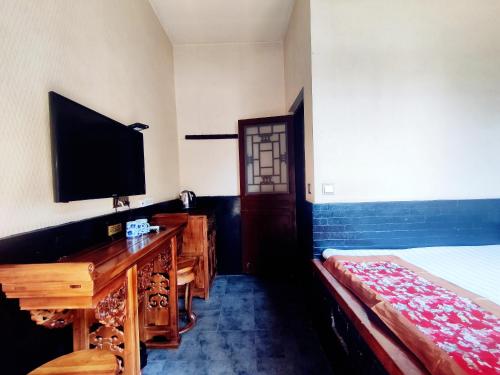 a bedroom with a bed and a desk and a television at Pingyao Xiangshengyuan Guest House in Pingyao