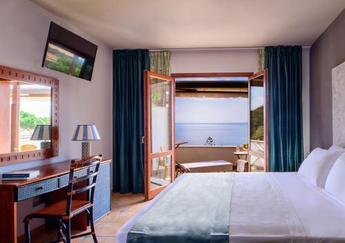 a hotel room with a bed and a desk and a window at Hotel Baia Imperiale in Campo nell'Elba