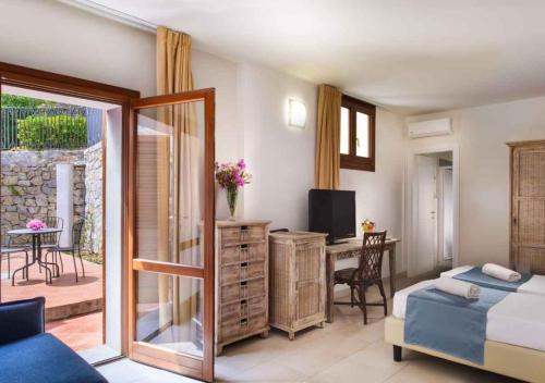 a bedroom with a bed and a desk with a television at Hotel Baia Imperiale in Campo nell'Elba