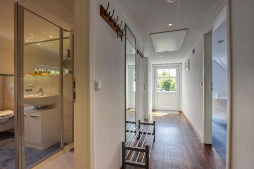 ein Flur mit einem Badezimmer mit Waschbecken und Spiegel in der Unterkunft Landhaus am Ufer - Wohnung 4 in Heiligenhafen